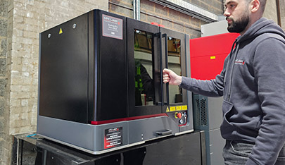 An image if the fibre laser cutter with a person next to it for scale