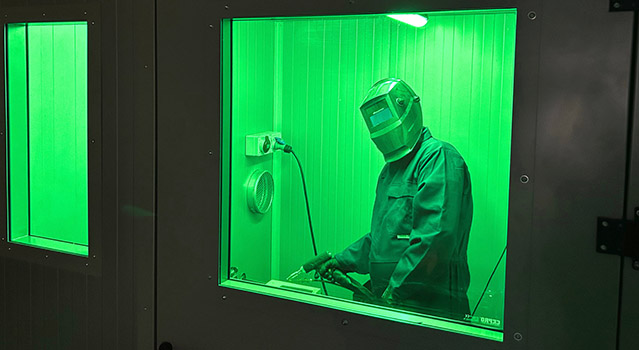 An image of a working using a laser welder in the welding booth